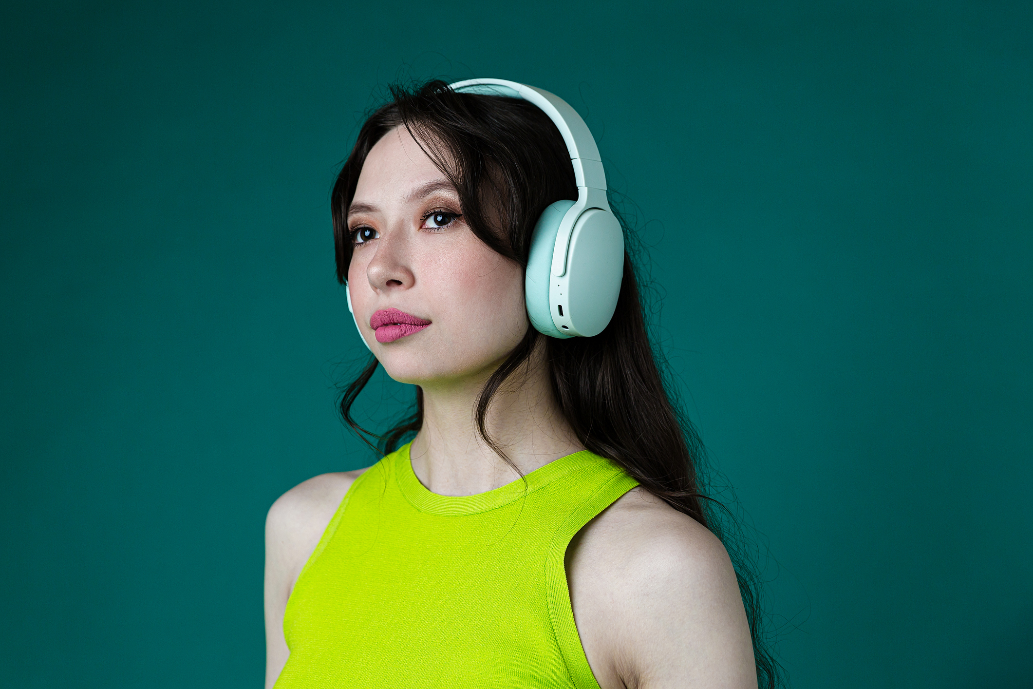 Joyful Woman in Neon Green Top Enjoying Music on Headphones